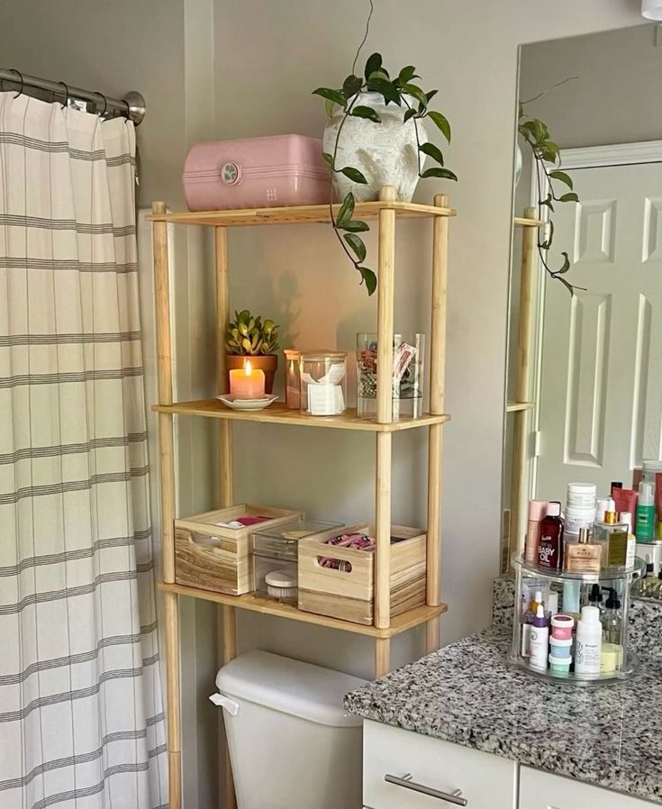 Bathroom corner with a wooden shelf, plants, candles, and toiletries for organized and relaxing ambiance.