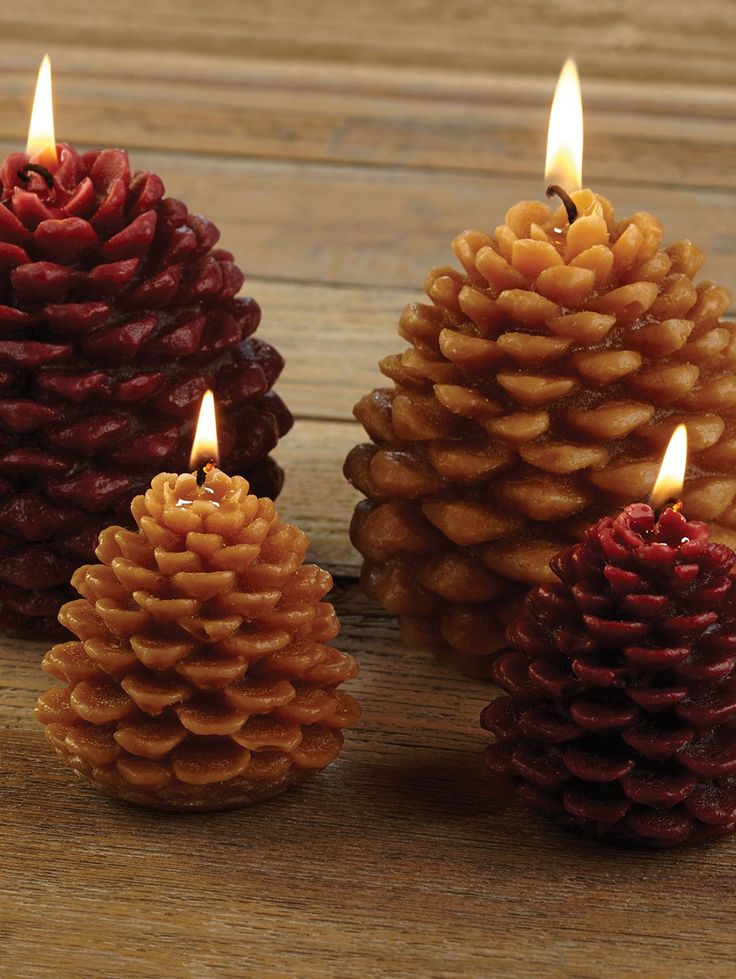 Pine cone-shaped candles on a wooden table, lit for a cozy and rustic atmosphere. Perfect for holiday decor.