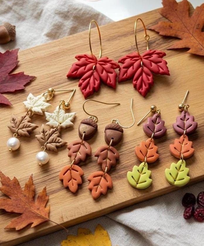 Colorful leaf and acorn earrings on a wooden board, showcasing autumn-themed jewelry with maple and oak leaf designs.