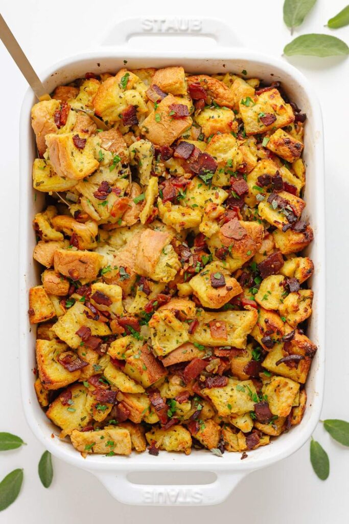 Savory bread stuffing with crispy bacon and herbs in a white casserole dish, perfect for a delicious holiday side dish.