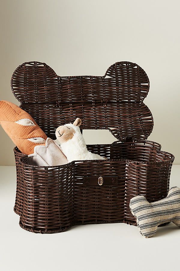 Dog bone-shaped wicker basket with plush toys inside, ideal for stylish pet toy storage. Perfect for pet owners looking to declutter.