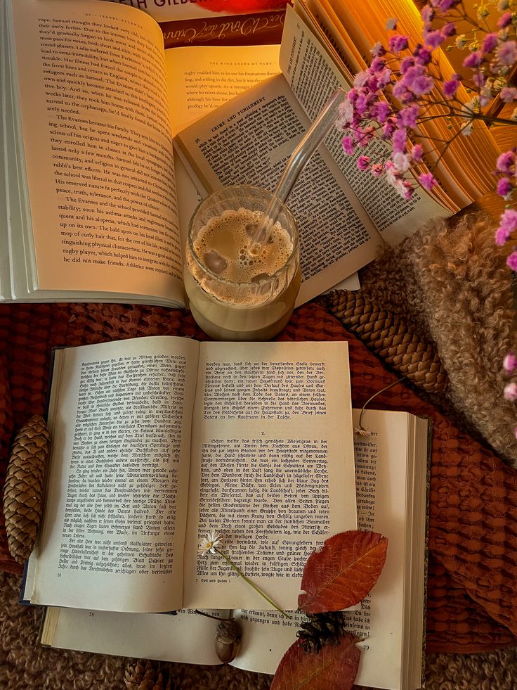 Cozy autumn reading nook with open books, iced coffee, and dried flowers, perfect for a relaxing literary escape.