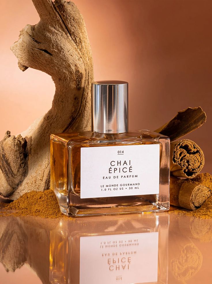 Elegant Chai Épicé perfume bottle surrounded by cinnamon sticks and driftwood on a warm, earthy background. Luxurious fragrance.