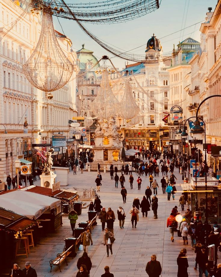 Bustling European street with festive decorations, historic architecture, and a lively crowd enjoying the vibrant city atmosphere.