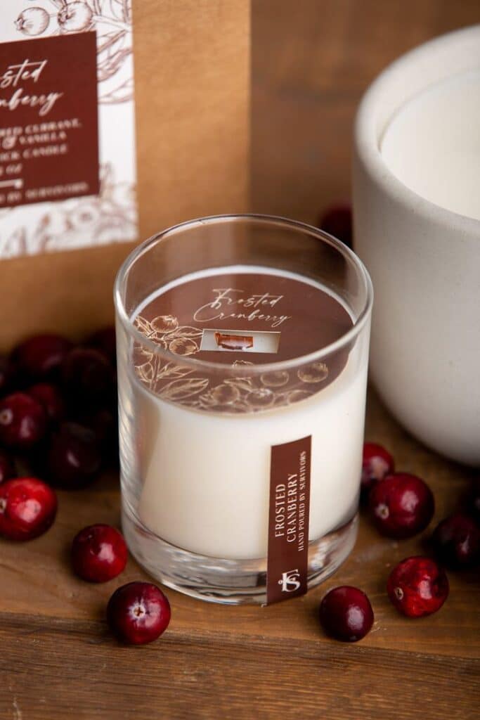 Frosted cranberry scented candle in glass jar with fresh cranberries, perfect for cozy home decor and aromatic ambiance.