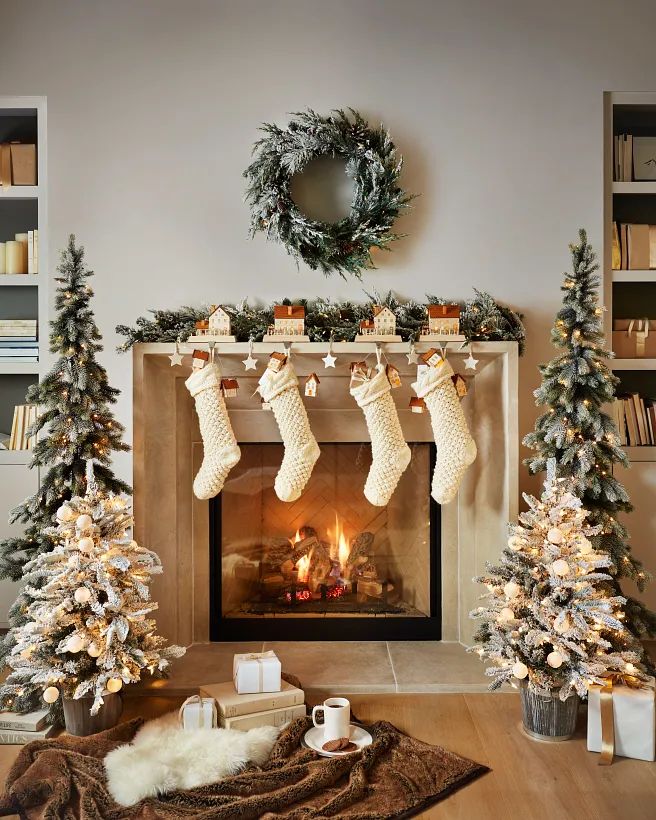 Cozy Christmas fireplace scene with stockings, lit trees, wreath, and gifts; a warm holiday decoration setting.