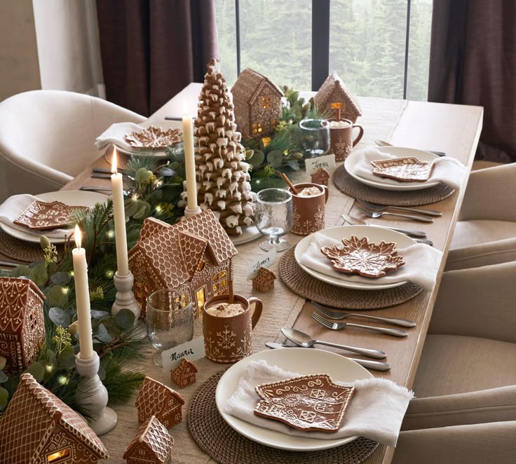 Festive holiday table setting with gingerbread houses, candles, and elegant tableware, creating a cozy and inviting atmosphere.