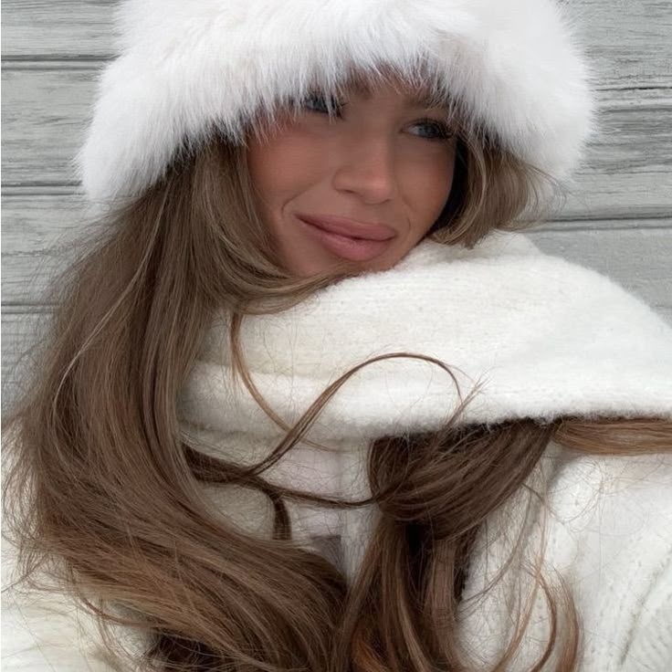 Woman in white fur hat and scarf smiles warmly, perfect for winter style inspiration.