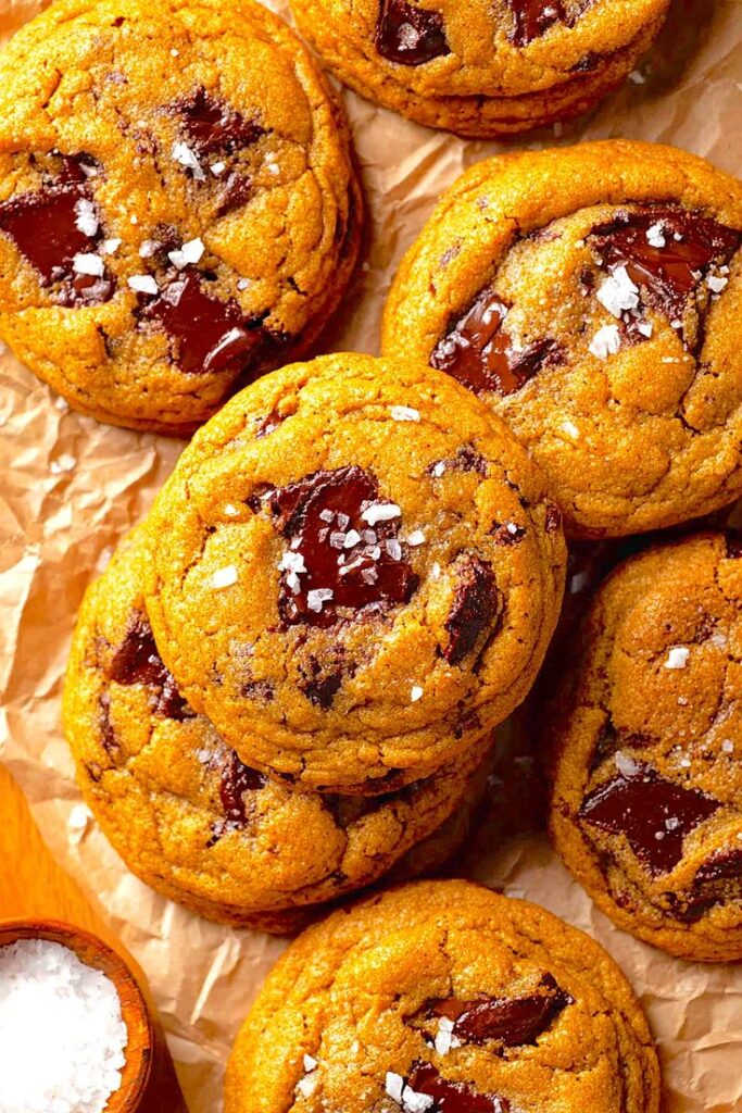 Close-up of freshly baked chocolate chip cookies with sea salt on parchment paper. Perfect for dessert lovers.