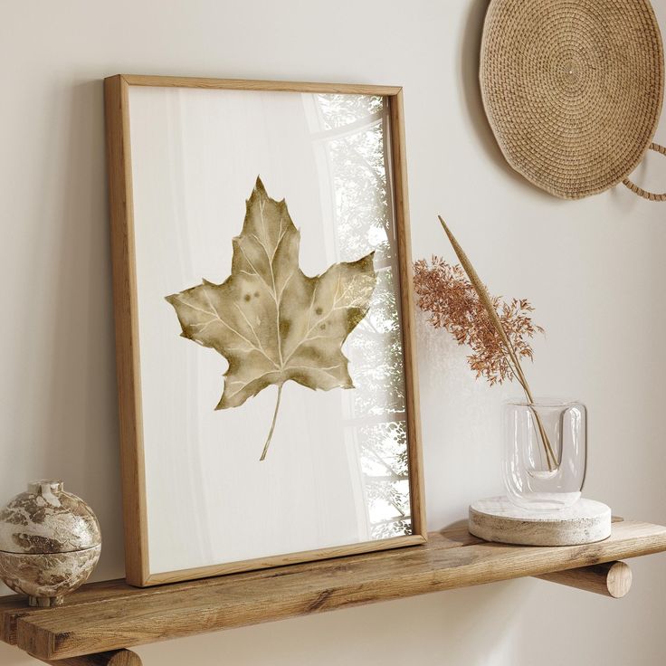 Framed autumn leaf art on wooden shelf with rustic decor, enhancing cozy home aesthetic and natural design elements.