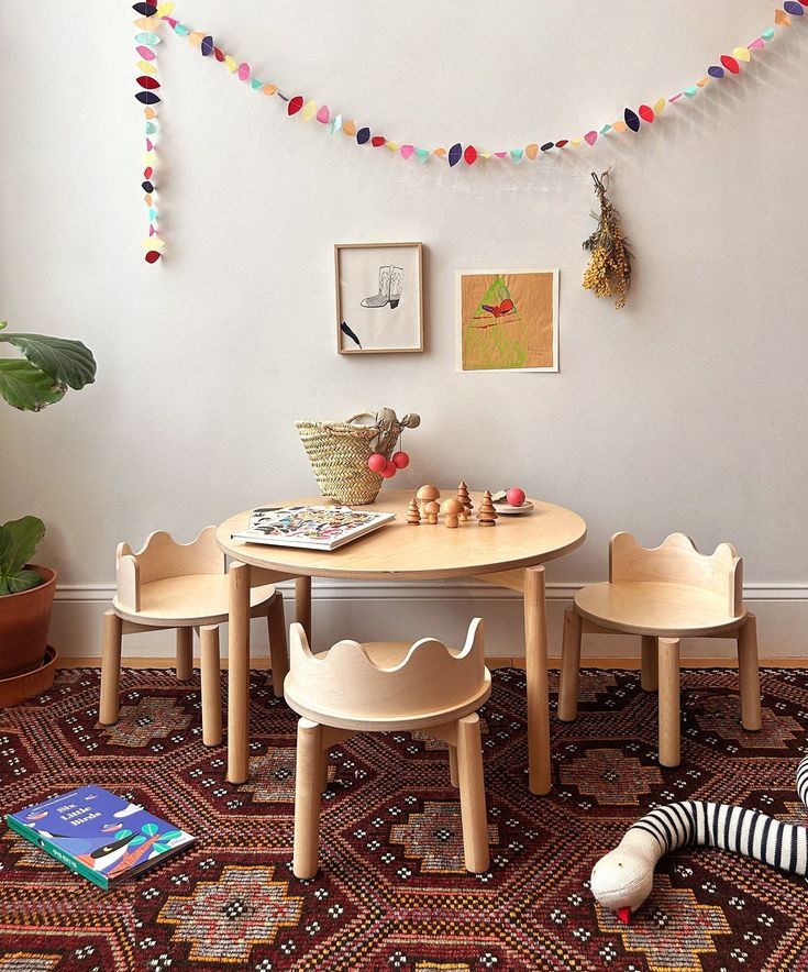 Cozy kids' playroom with wooden table, chairs, and colorful decor. Stylish art and books add charm to the playful space.