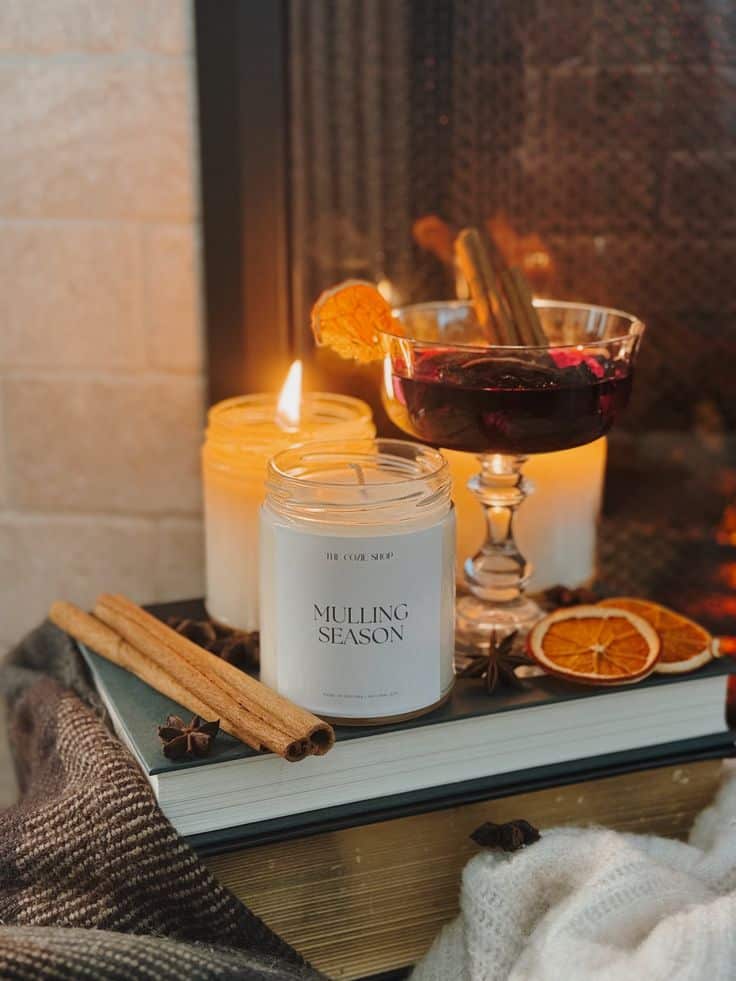 Cozy autumn scene with mulling spices, candles, and mulled wine by the fireplace, evoking warmth and comfort.