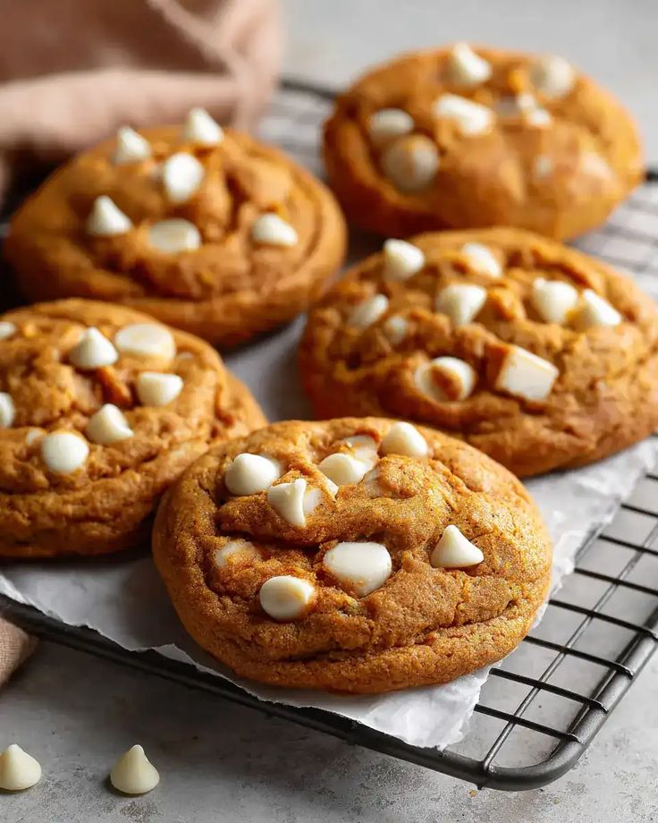 Freshly baked cookies with white chocolate chips on a cooling rack, perfect for dessert lovers.