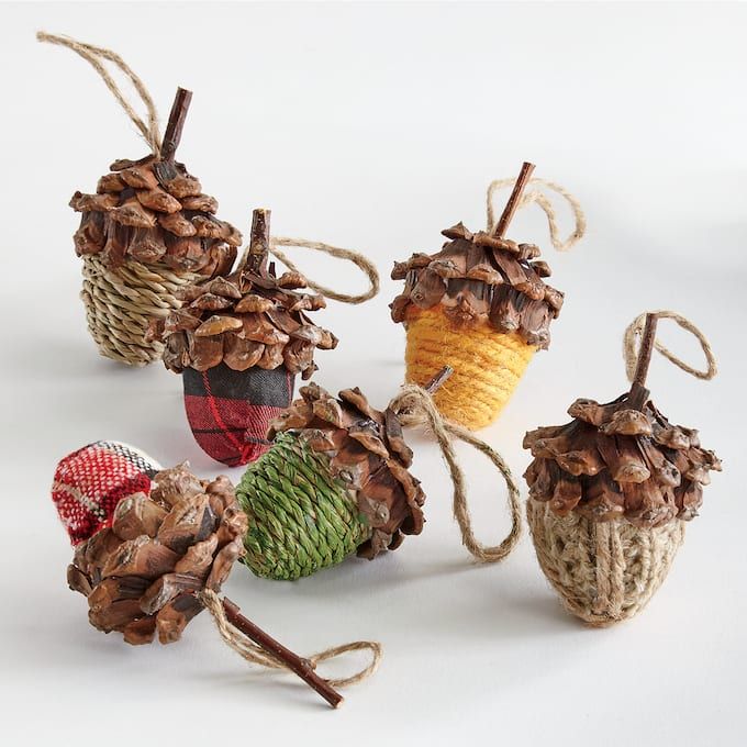 Handmade acorn ornaments with pine cone tops, wrapped in colorful yarn and patterns, perfect for rustic and festive home decor.
