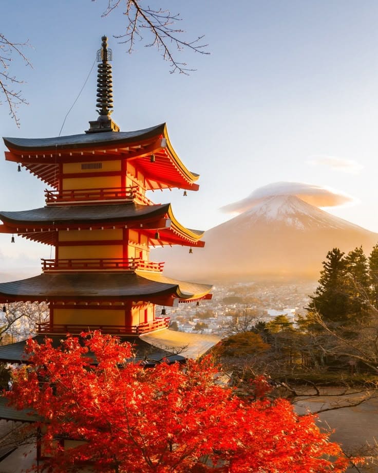 Pagoda with vibrant red autumn leaves and Mount Fuji in the background, set under a serene sunrise sky in Japan.
