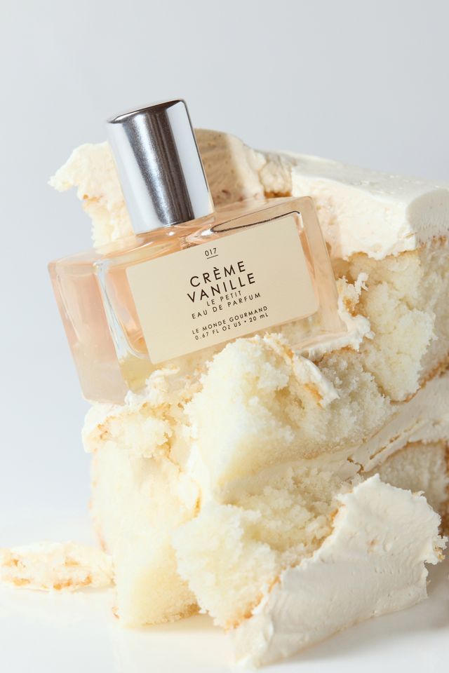 Crème Vanille Eau de Parfum bottle surrounded by creamy vanilla cake, luxury fragrance display.