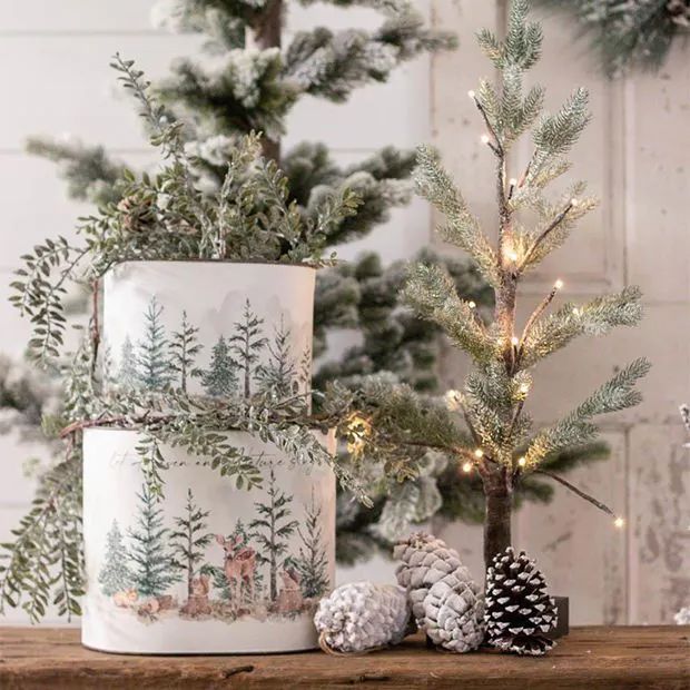 Festive winter decor with a mini lit Christmas tree, pinecones, and forest-themed elements on a rustic wooden surface.