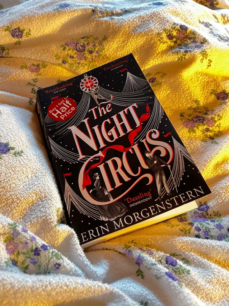 The Night Circus book on a floral blanket, cozy reading setting, soft morning light.