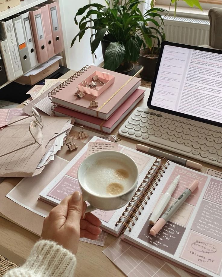 Cozy workspace with a coffee, notebooks, laptop, and plants. Ideal for productivity and planning. Elegant pink and beige tones.