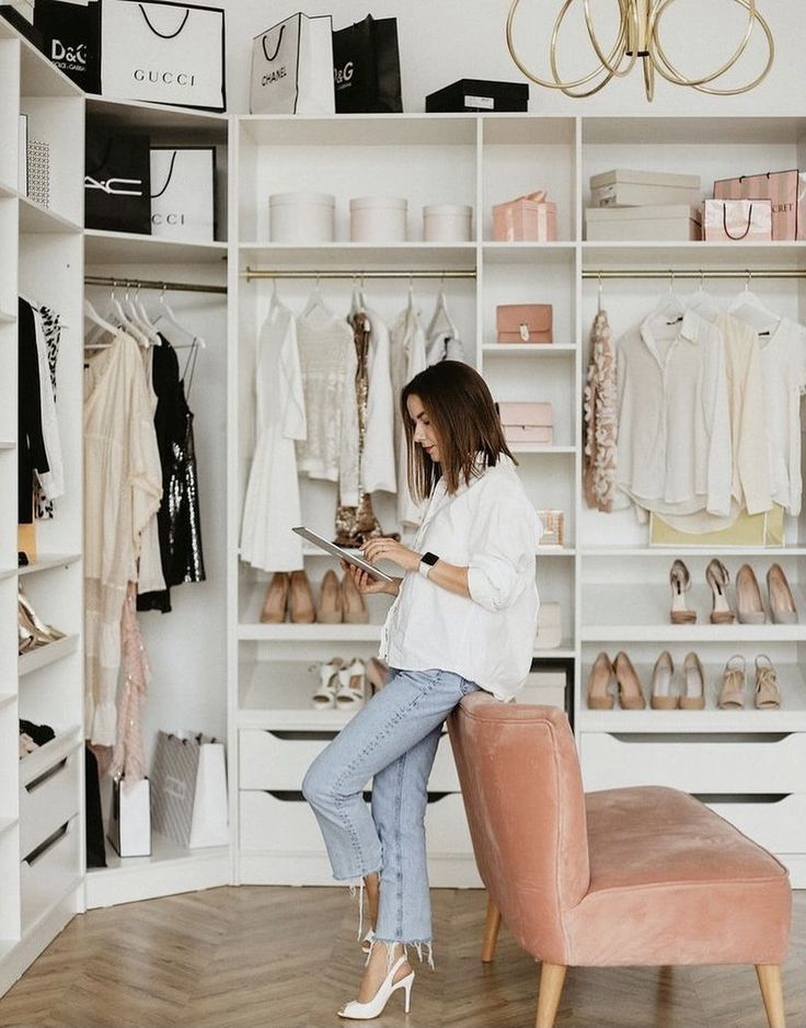 Woman in stylish walk-in closet, organizing luxury fashion items and accessories. Modern wardrobe interior design.