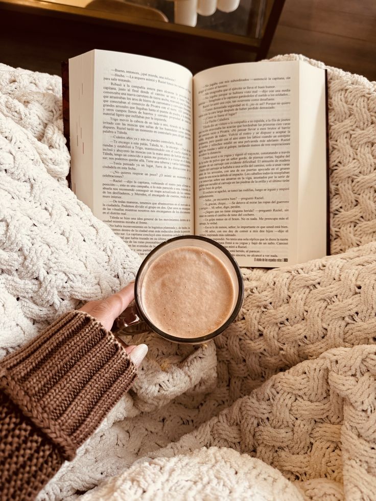 Cozy setup with an open book, cup of coffee, and a knitted blanket, perfect for a relaxing reading session.