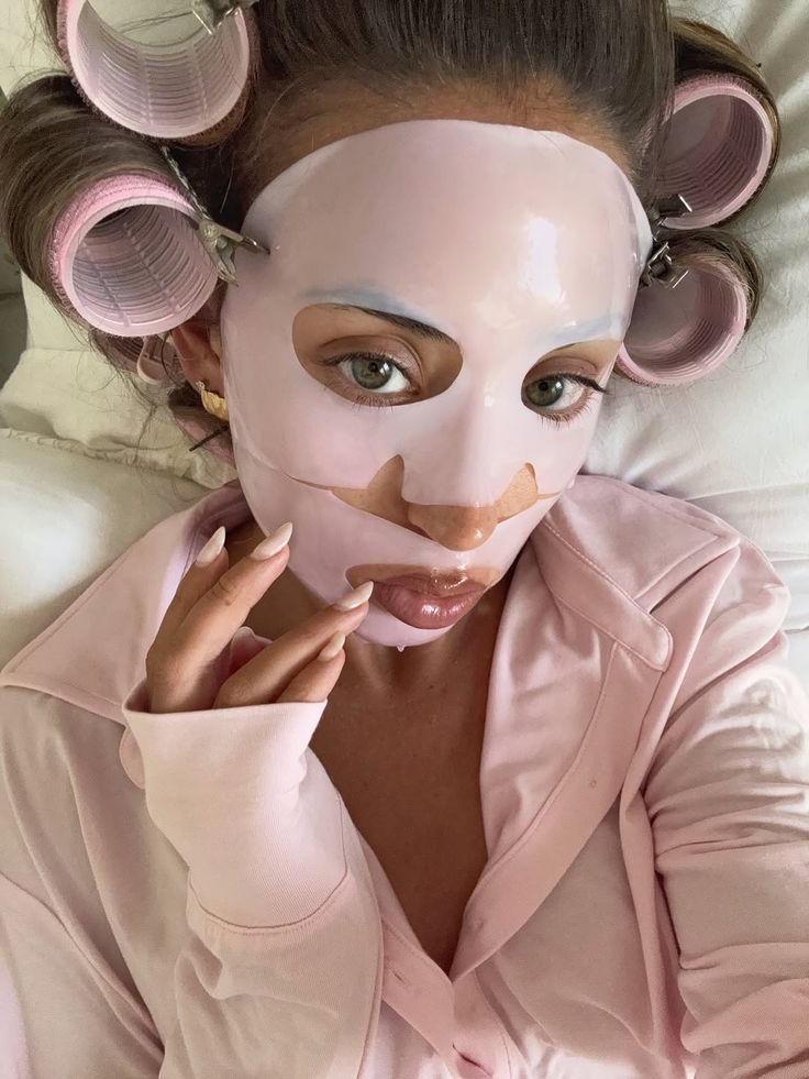 2 Instagram - Handy Home Woman wearing a pink face mask and curlers, relaxing in a matching pink robe. Skincare and pampering at home.