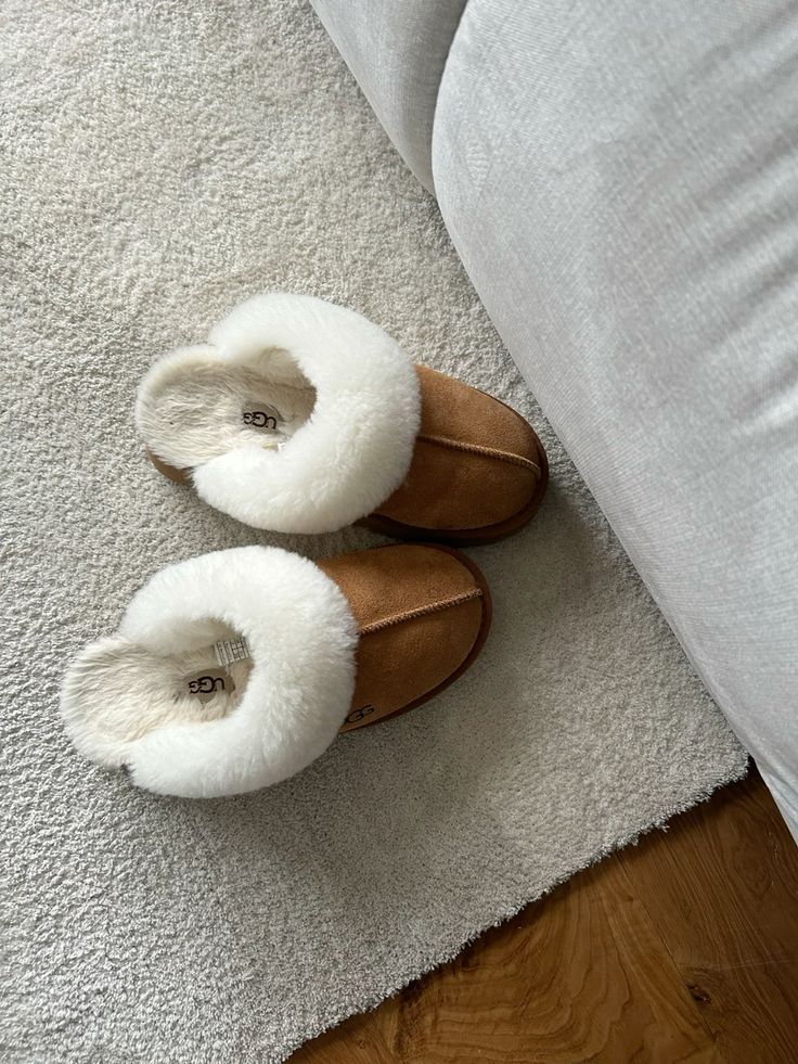 30c200e5-a898-4a3a-a127-b2c7b4356f80 - Handy Home Cozy brown slippers with white fur lining on a soft cream carpet near a gray sofa, perfect for relaxing at home.