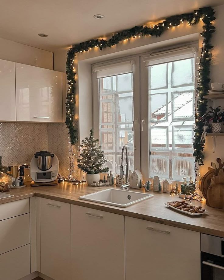 3fc86249-d16b-42ca-83d5-e3abc917dcbb - Handy Home Cozy kitchen decorated for Christmas with garlands, mini tree, and festive lights around the window, creating a warm holiday atmosphere.
