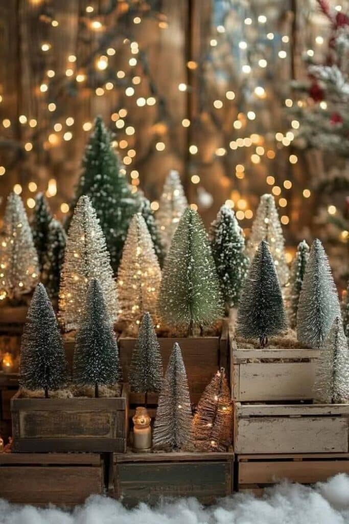 4f15c1db-7aa5-48fb-b877-55cca23166a7 - Handy Home Miniature snowy Christmas trees on wooden crates, surrounded by warm fairy lights, creating a cozy festive scene.