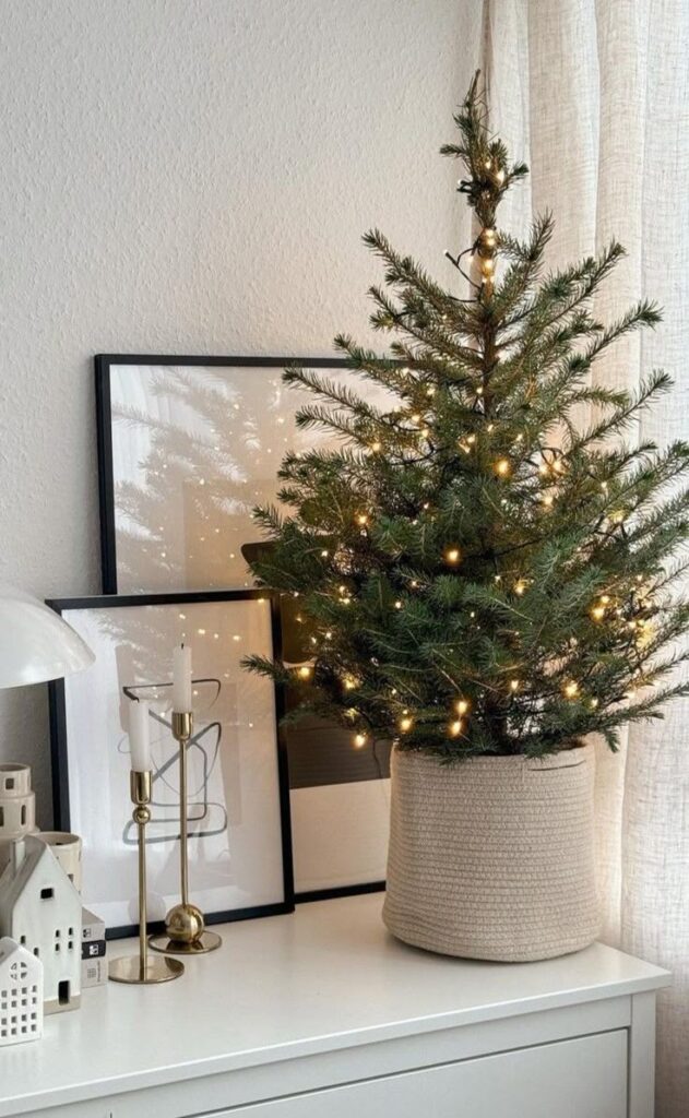 5b9c8fed-c3ad-4645-b390-d35d5e9ee63a - Handy Home Mini Christmas tree with lights on a white dresser, surrounded by modern decor, framed art, and candles. Cozy holiday decor.