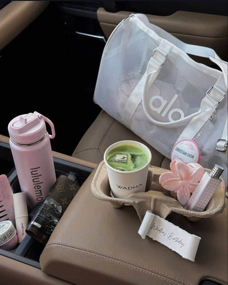 Trendy car essentials including a Lululemon bottle, Alo Yoga bag, and matcha latte create a chic on-the-go lifestyle vibe.