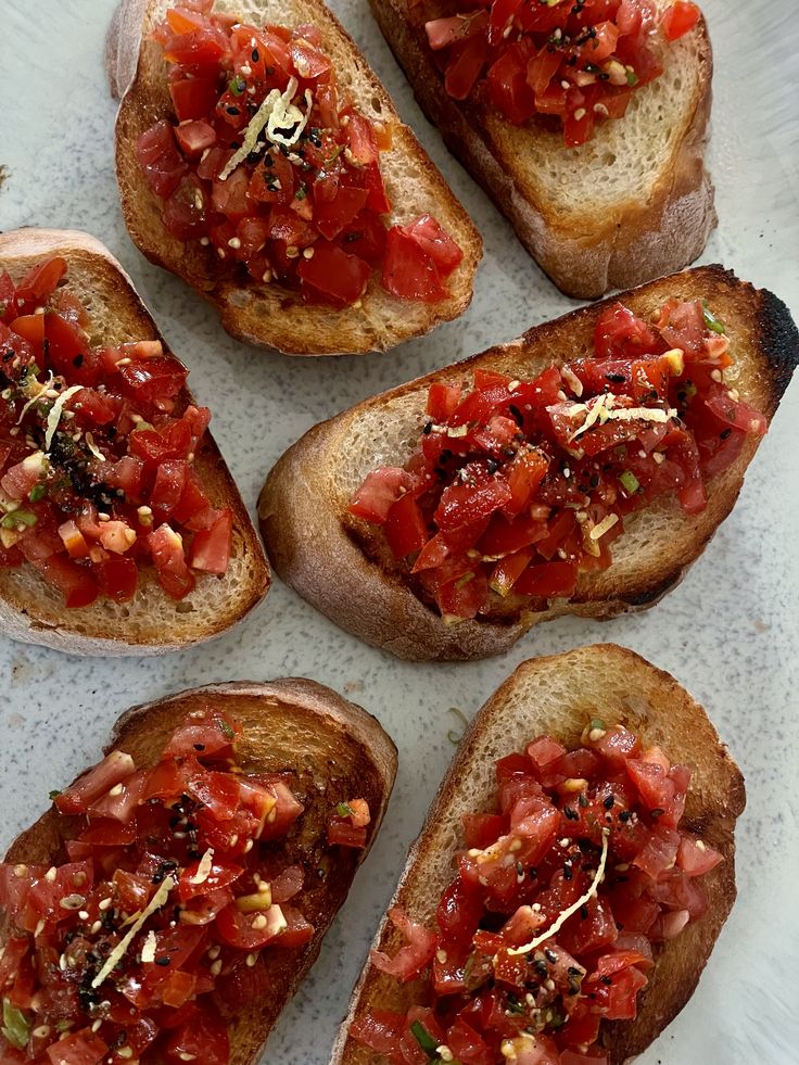 Bruschetta - Handy Home Toasted bruschetta topped with fresh diced tomatoes, herbs, and seasonings on a white plate. Perfect appetizer for any meal.