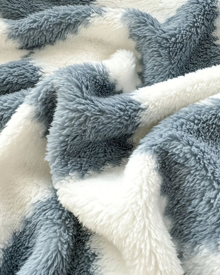 Soft, fluffy blue and white blanket with cozy, plush texture. Perfect for home decor and warmth.