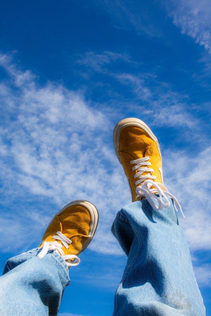 Color Contrast and Harmony in Photography - Handy Home Yellow sneakers and blue jeans against a clear blue sky with wispy clouds; youthful and carefree vibe.
