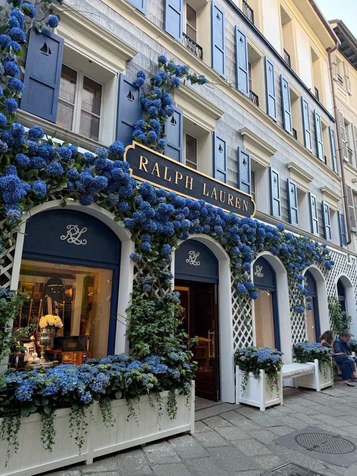 Ralph Lauren store with blue hydrangea decor on elegant building facade in city street.