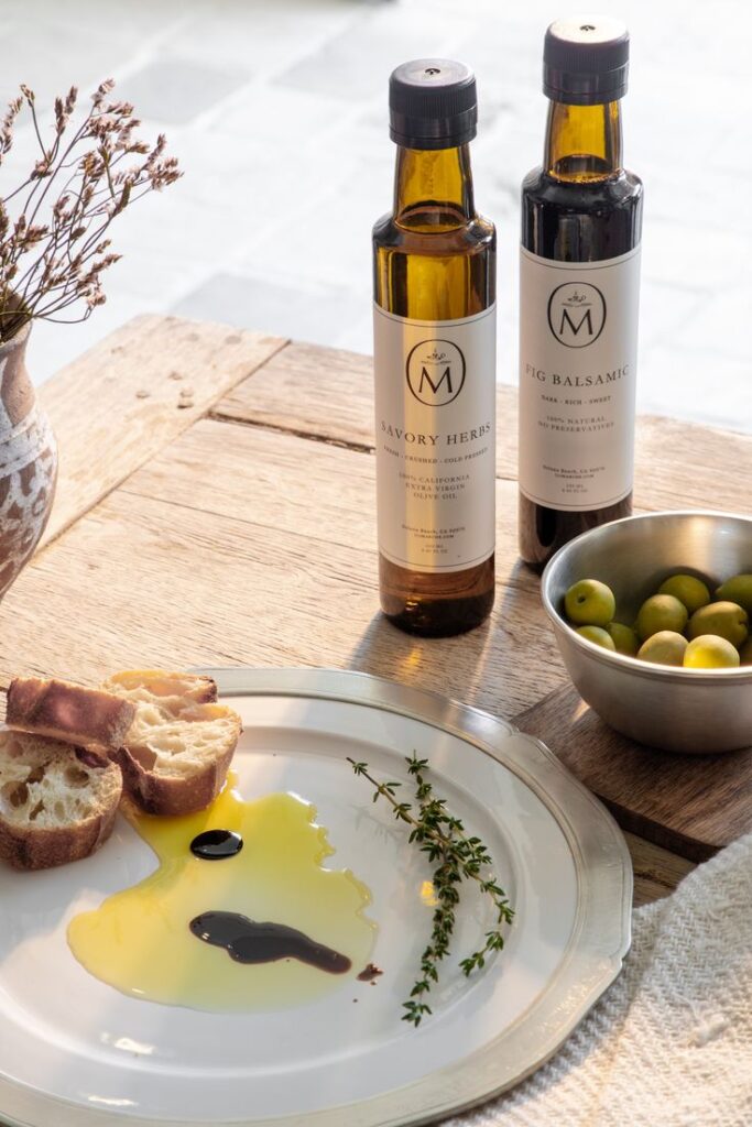 Gourmet olive oil and balsamic vinegar with artisan bread and olives on a wooden table; perfect for a Mediterranean feast.