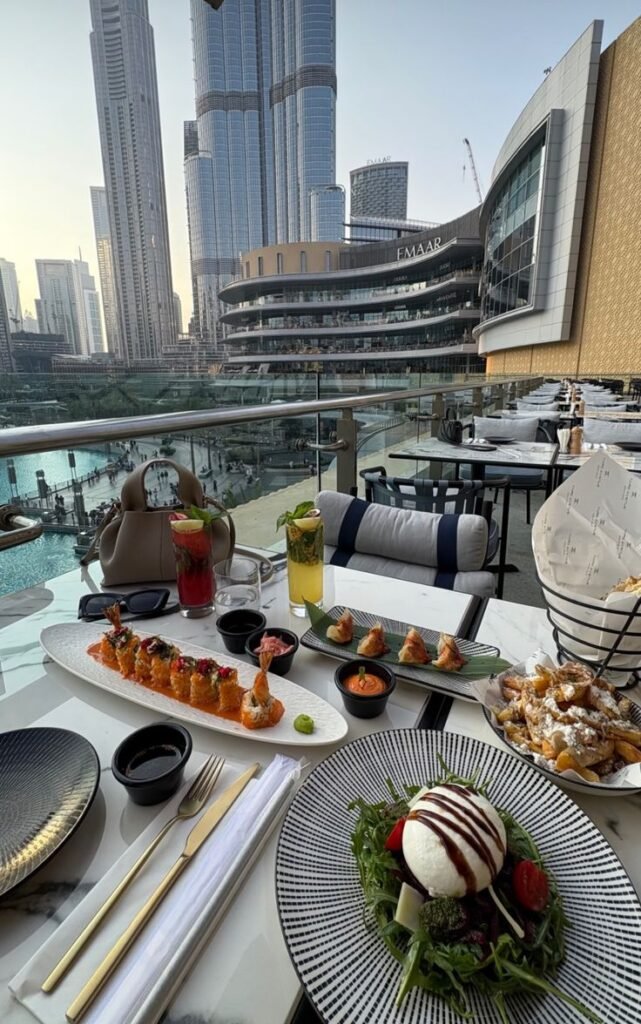 Luxurious dining with sushi and salad overlooking stunning skyscrapers and a serene waterfront patio setting.