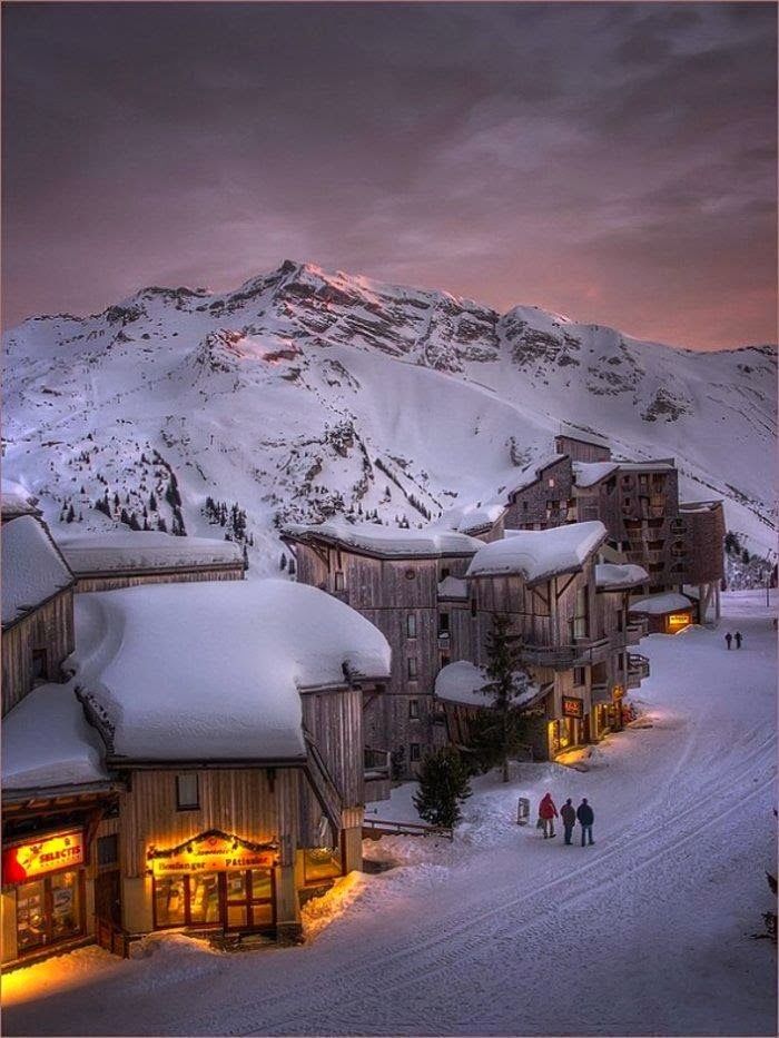 Roros Norway - Handy Home Snowy village at sunset with mountain backdrop, illuminated shops, and people walking on snow-covered streets. Cozy winter atmosphere.