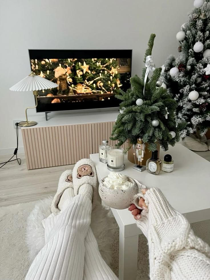 Cozy winter scene with slippers, hot chocolate, and Christmas tree decorations, perfect for holiday relaxation at home.
