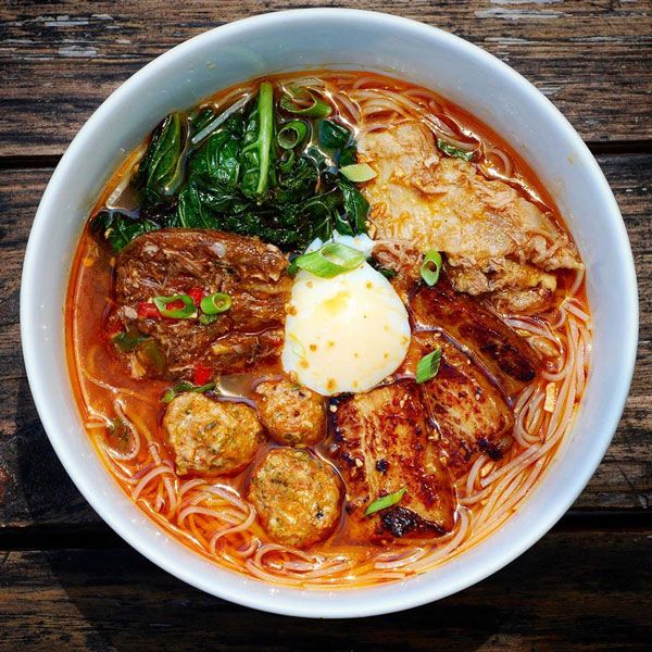 The Best Places to Eat in New Orleans - Handy Home Delicious bowl of spicy ramen with grilled meats, leafy greens, and a soft-boiled egg on wooden table.