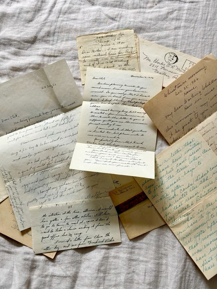 Old handwritten letters and envelopes scattered on a white cloth, showcasing vintage correspondence and calligraphy.
