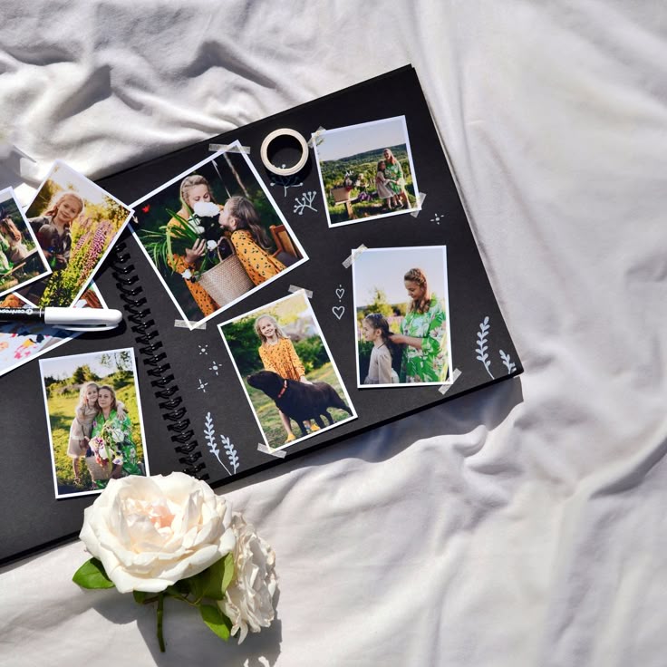 Open scrapbook on white fabric with family photos and a white rose nearby.