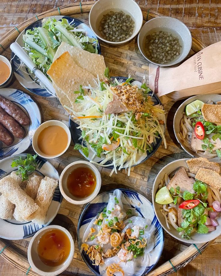 Vietnamese cuisine - Handy Home Assorted Vietnamese dishes on a bamboo tray, featuring salads, rolls, soups, and fresh herbs, perfect for a traditional feast.