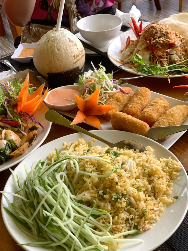 Vietnamese food 🫶🏻 vietnam vietnamtravel - Handy Home A vibrant Thai meal featuring fried rice, spring rolls, salad, and fresh coconut, perfect for a delicious tropical dining experience.