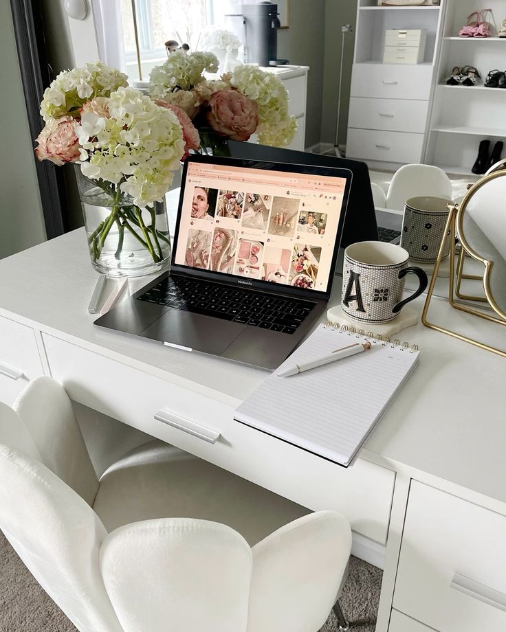 alexandraxcorrine - Handy Home Home office desk with laptop, notebook, coffee mug, and flowers. Modern workspace setup with elegant decor and natural light.