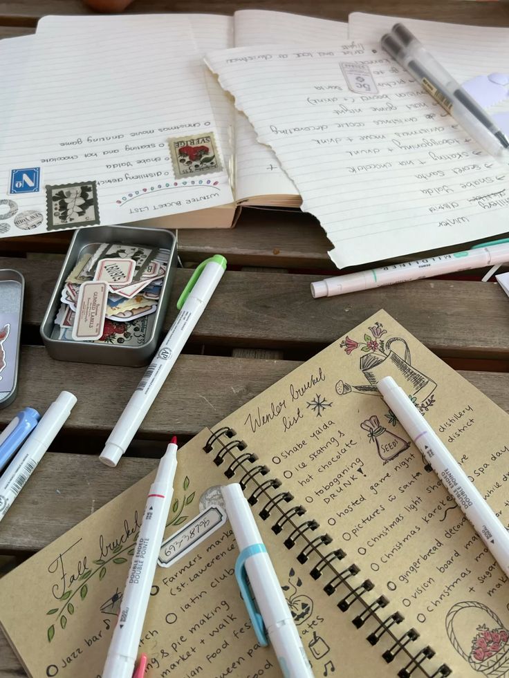 Creative bullet journaling with colorful markers and stickers on a wooden desk, featuring fall and winter bucket lists.