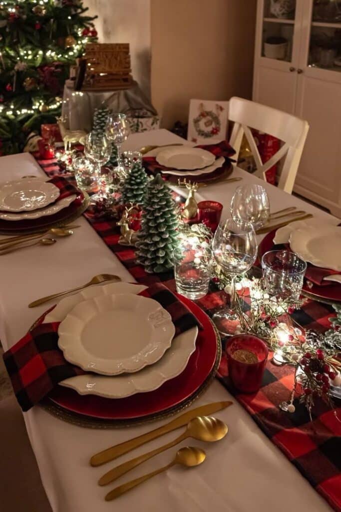 cf2b25c2-53c5-43d0-9846-a894ad6fc8a3 - Handy Home Festive Christmas dinner table setting with plaid accents, golden cutlery, elegant dishware, and glowing string lights.