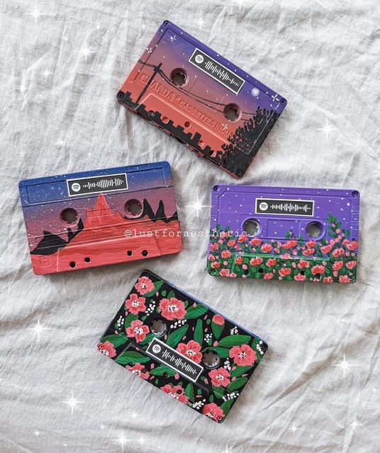 Colorful artistic cassette tapes with nature-inspired designs on a textured fabric background.