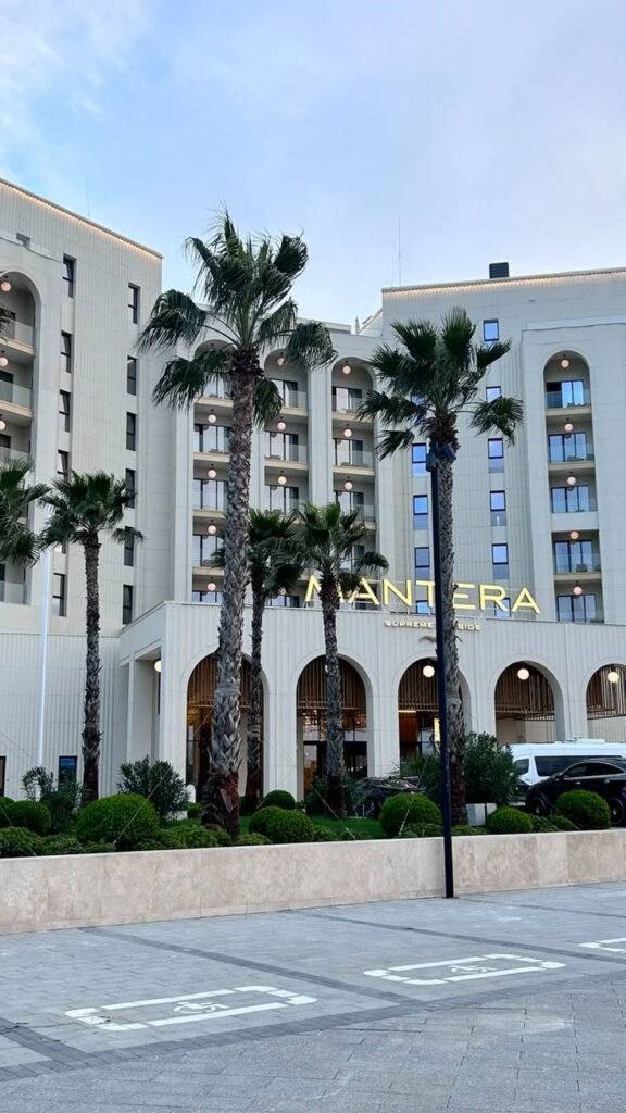 Modern hotel facade with balconies and palm trees under a clear sky, offering a luxurious and inviting atmosphere.