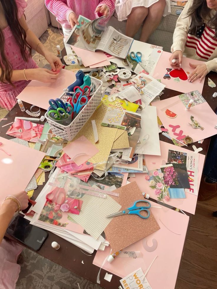 Group crafting session with scissors, magazines, and colorful paper for creative scrapbooking projects on a messy tabletop.